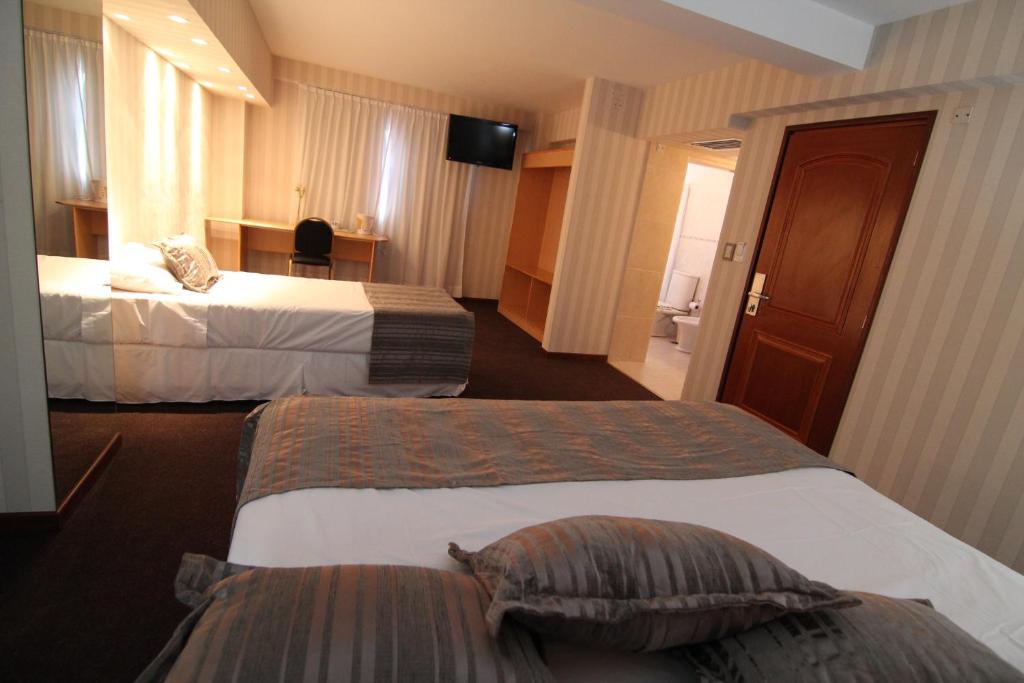 ein Hotelzimmer mit 2 Betten und einem TV in der Unterkunft Hotel El Cortijo in Neuquén