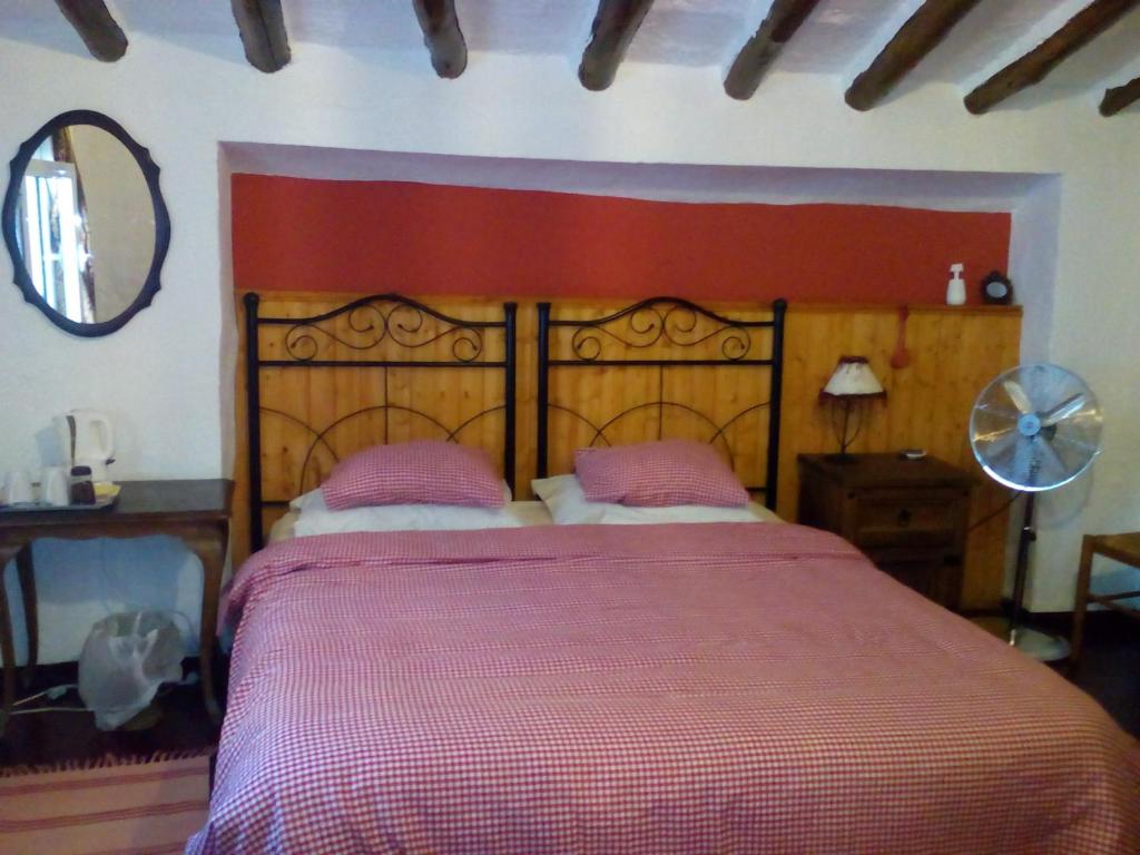 1 dormitorio con 1 cama grande y cabecero rojo en Casa La Rosa, en Almedinilla