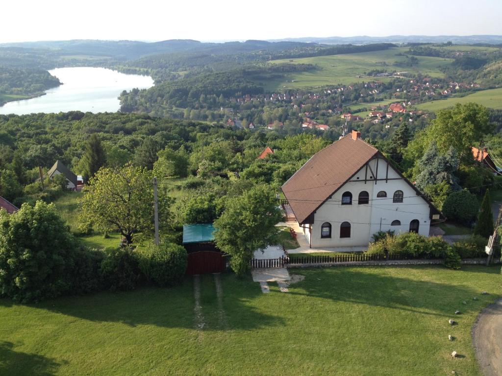 biały kościół na zielonym polu z jeziorem w obiekcie Anita Apartmanház w mieście Orfű
