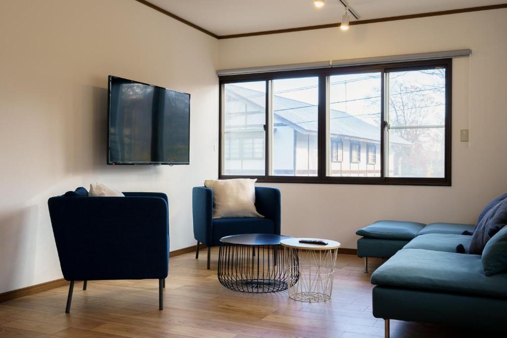 a living room with two blue chairs and a table at Forest and Stars Akakura Sauna in Myoko