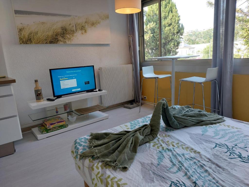 - une chambre avec un lit, une télévision et des chaises dans l'établissement Studio Le Trident de la mer - Axelle Loc'Appart, à Cannes