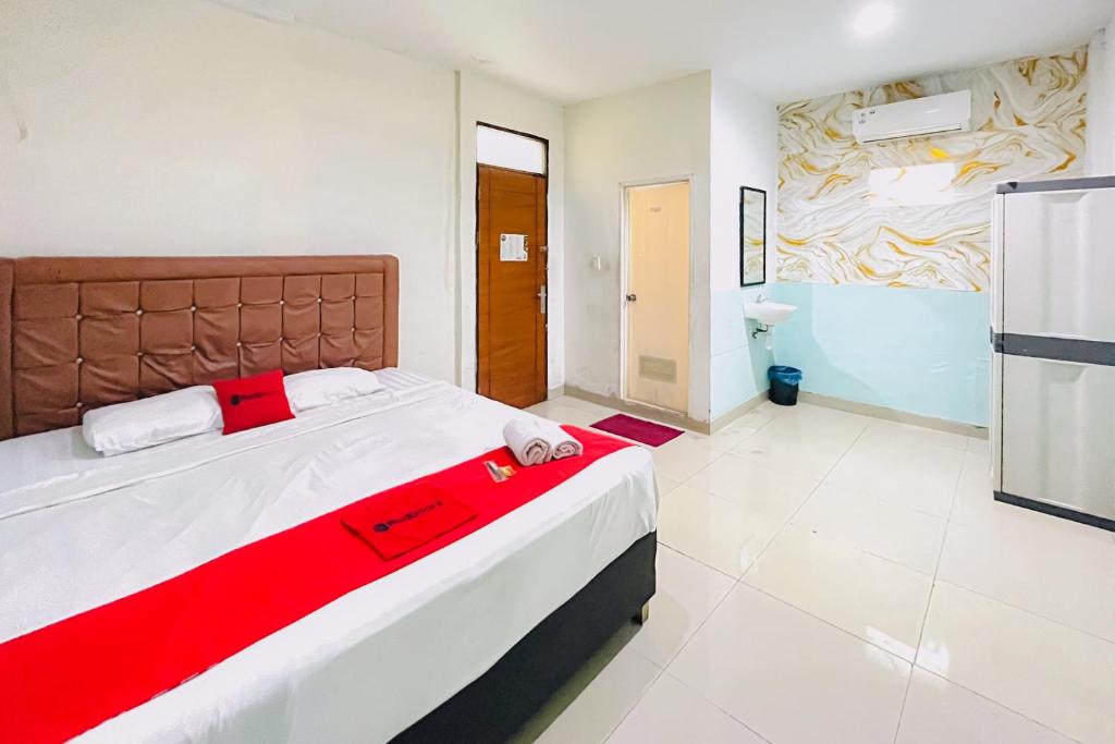 a bedroom with a large bed with a red blanket at RedDoorz at STM Suite Medan Amplas in Medan