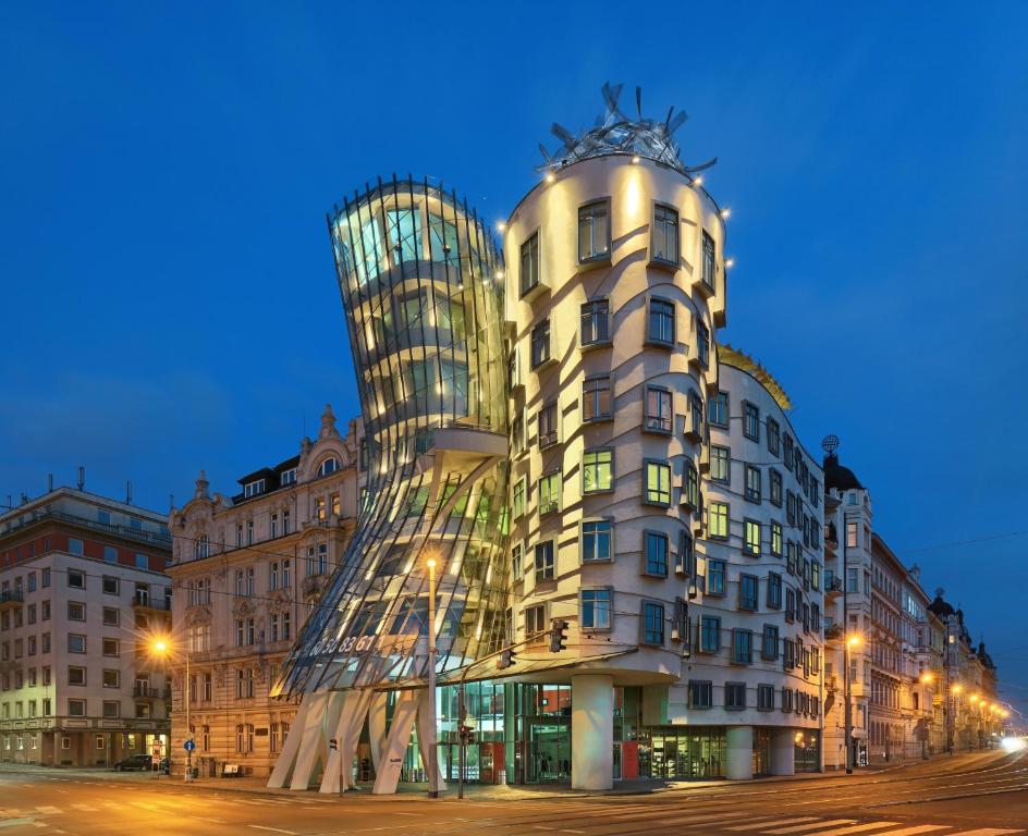 a building with a glass facade in a city at Dancing House - Tančící dům hotel in Prague