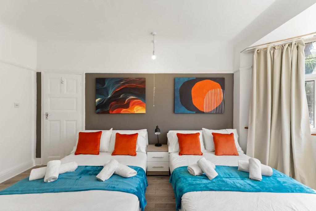 2 Betten in einem Zimmer mit orangefarbenen und weißen Kissen in der Unterkunft Stylish 5 Bed Home in Forest Hill by Amber Stays, Perfect for Business & Contractors Sleeps 16 in Forest Hill