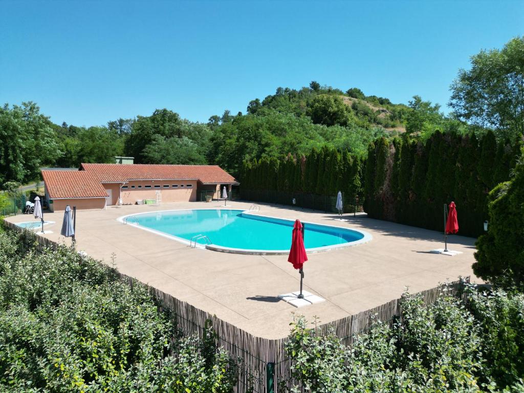 a swimming pool with two umbrellas in a yard at Camping Onlycamp Le Pré in Montaigut-le-Blanc