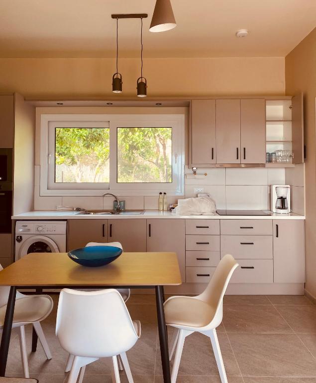 a kitchen with a wooden table and white chairs at Villa Banana in Lourdata