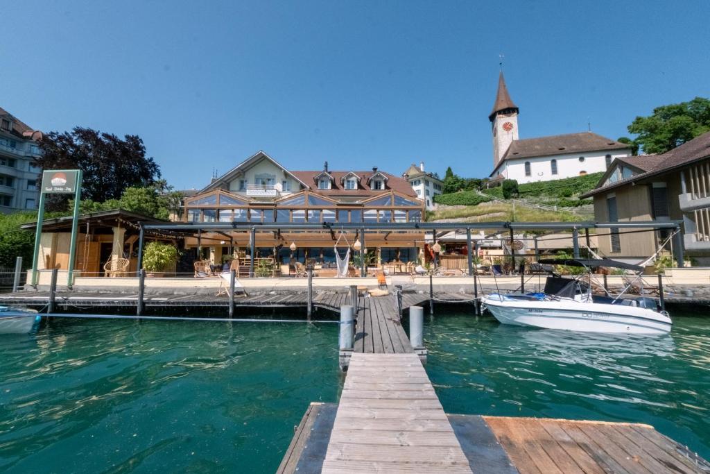 a boat is docked at a dock with a building at Room's at HAUS am SEE direkt am Thunersee gelegen mit SELF CHECK IN & digitaler Rezeption in Oberhofen am Thunersee