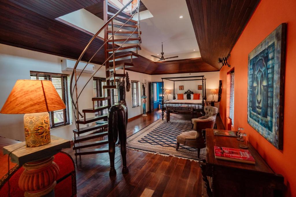 a living room with orange walls and a spiral staircase at Madilina Heritage Villa in Parūr
