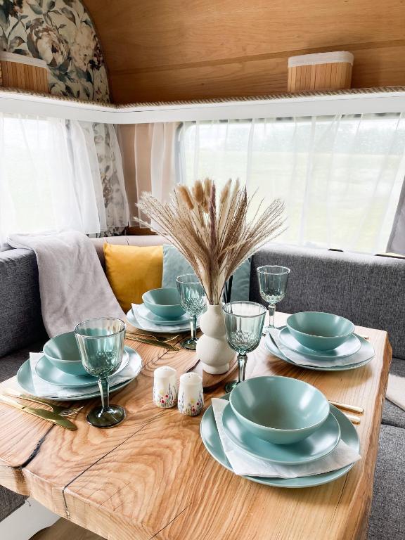 a wooden table with plates and wine glasses on it at Majakatare Holiday Homes in Maasi