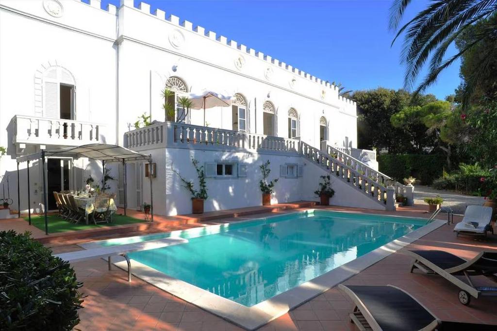 a swimming pool in front of a white house at Villa della Contessa Cangini di Volterra con piscina e parco privato in Castiglioncello