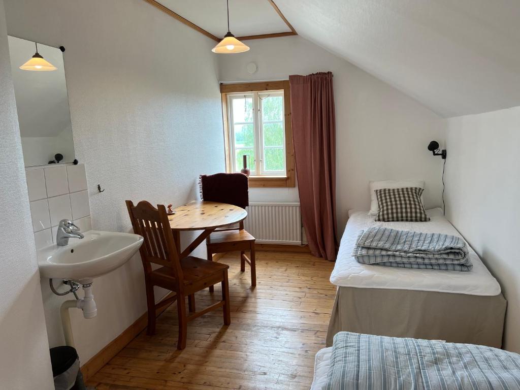 a room with a sink and a bed and a table at Humletorkan Vandrarhem in Näsum