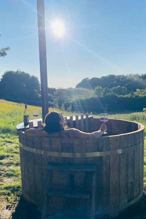 a woman laying in a barrel with a glass of wine at Glamping with outdoor wood-fired hot tub in Vissenbjerg