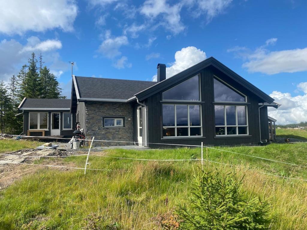 a house with a person sitting in front of it at MYLLA - New cabin - Sauna - Hike - Bike - Canoe- Fishing in Jevnaker