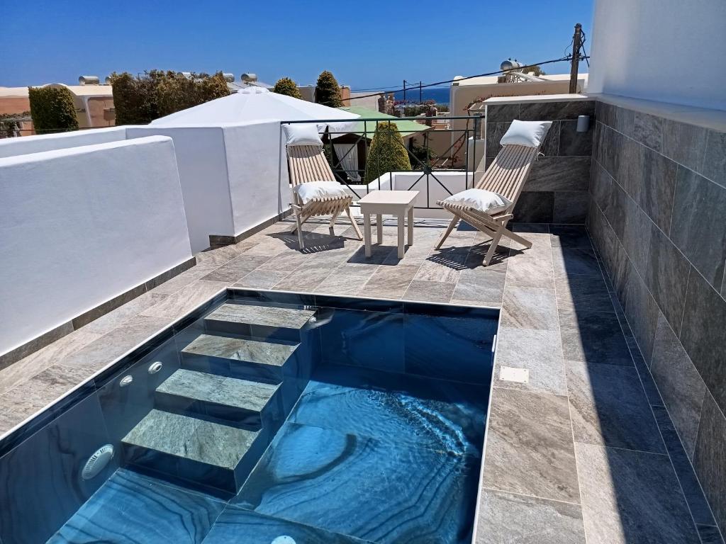 a swimming pool on a patio with chairs and a table at Chariot Apartments Santorini in Kamari