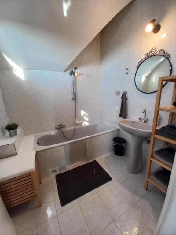 Un baño con bañera, lavabo y espejo. en Silenzio Apartman, en Gyula