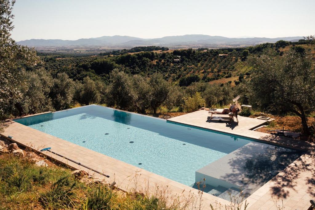 a person sitting on a chair next to a swimming pool at Stargazer - Glamping Maremma, Toscana in Roccastrada