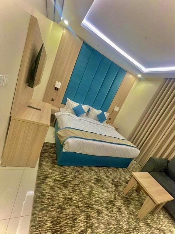 a bedroom with a blue bed and a couch at جود المدينة للإجنحة الفاخرة in Medina