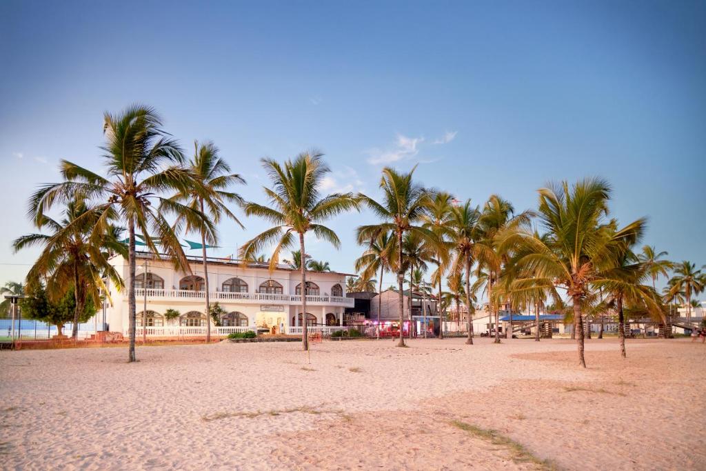 una spiaggia con palme di fronte a un edificio di Hotel Albemarle Galapagos Beachfront a Puerto Villamil