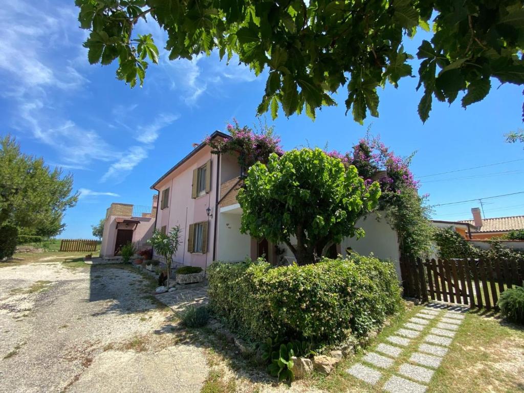 a pink house with a tree and bushes at Il Casale di Nonna Bambina in Francavilla al Mare