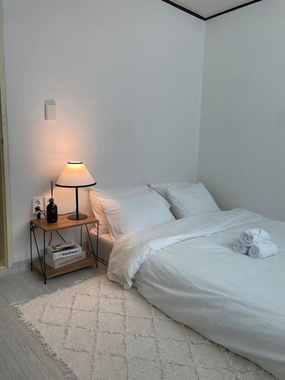 1 dormitorio con 1 cama blanca con lámpara y mesa en Letters Share House, en Wonju