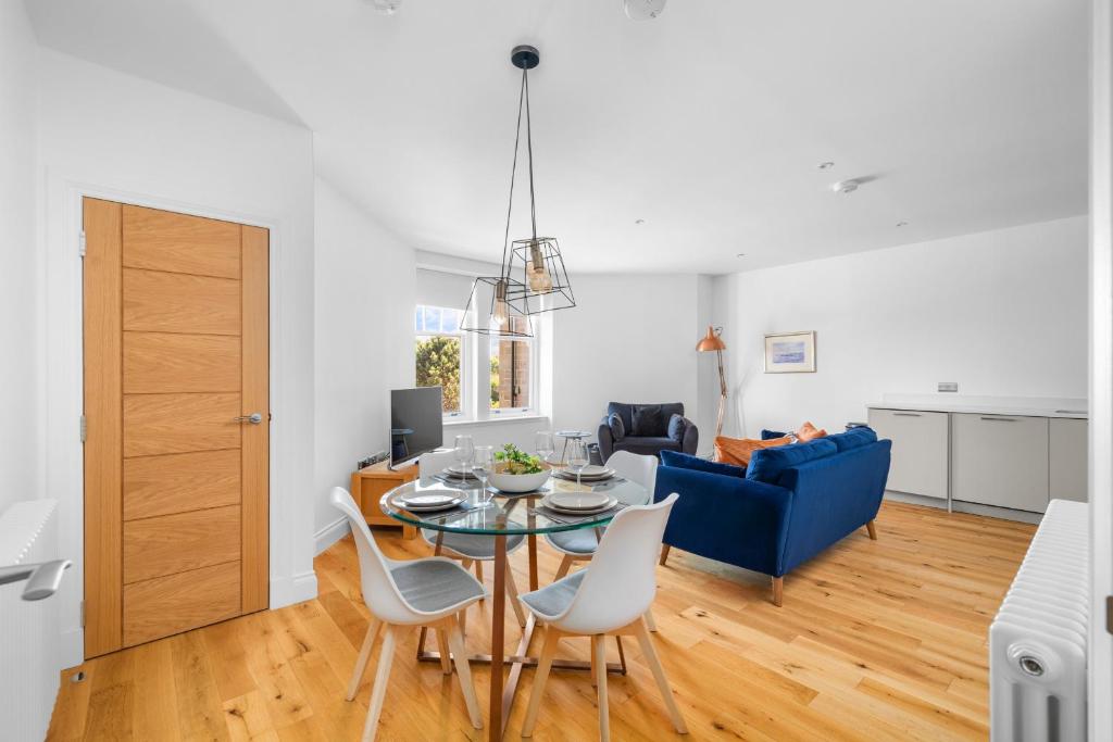a living room with a table and chairs and a blue couch at Panmure Apartment in Monifieth