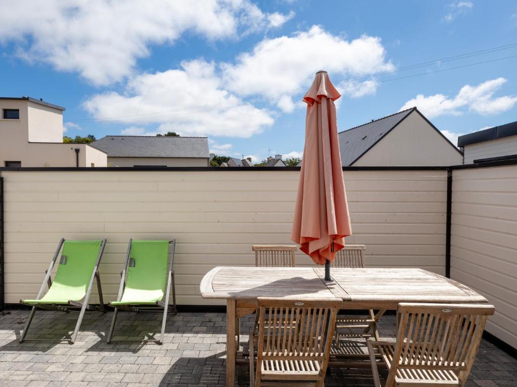 a table and chairs with an umbrella on a patio at Ty Ker by Madame Est Servie in Pleumeur-Bodou