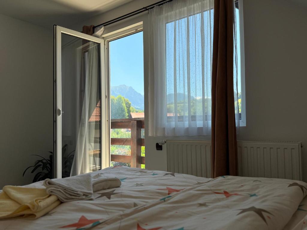a bedroom with a bed and a large window at Casuta cu Dumbrava in Bran