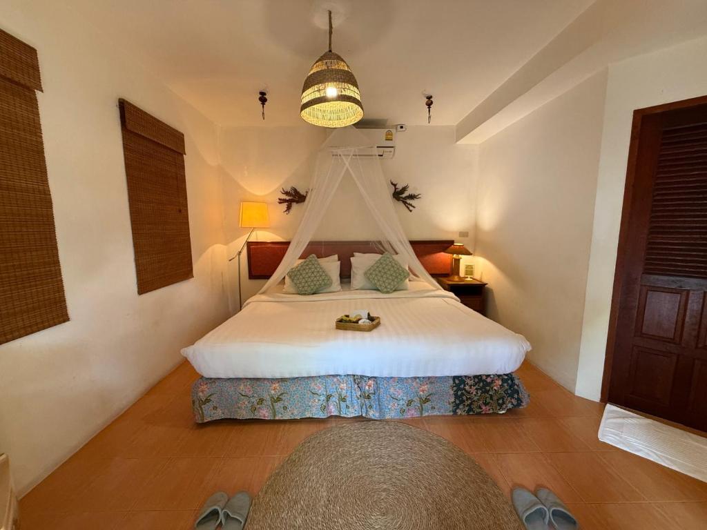 ein Schlafzimmer mit einem weißen Bett mit Himmelbett in der Unterkunft Natural Wing Health Spa and Resort in Ban Bang Po