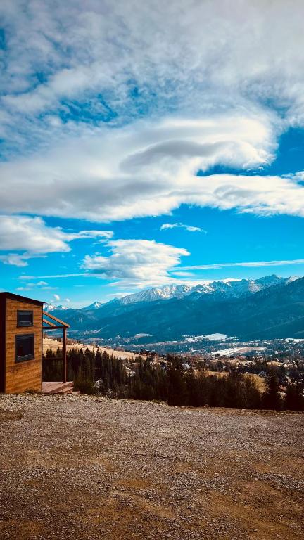 a small cabin in a field with mountains in the background at Flow Hill in Kościelisko