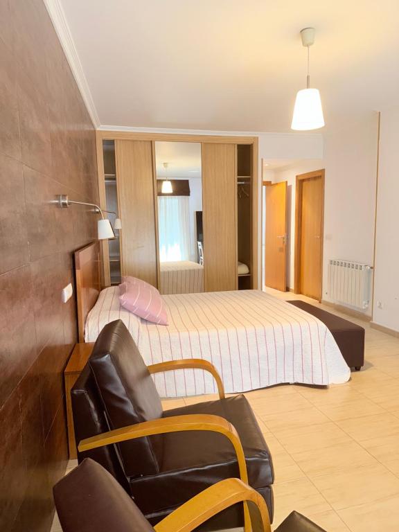 sypialnia z łóżkiem, krzesłem i kanapą w obiekcie Hostal Restaurante Pinarejo w mieście A Lanzada