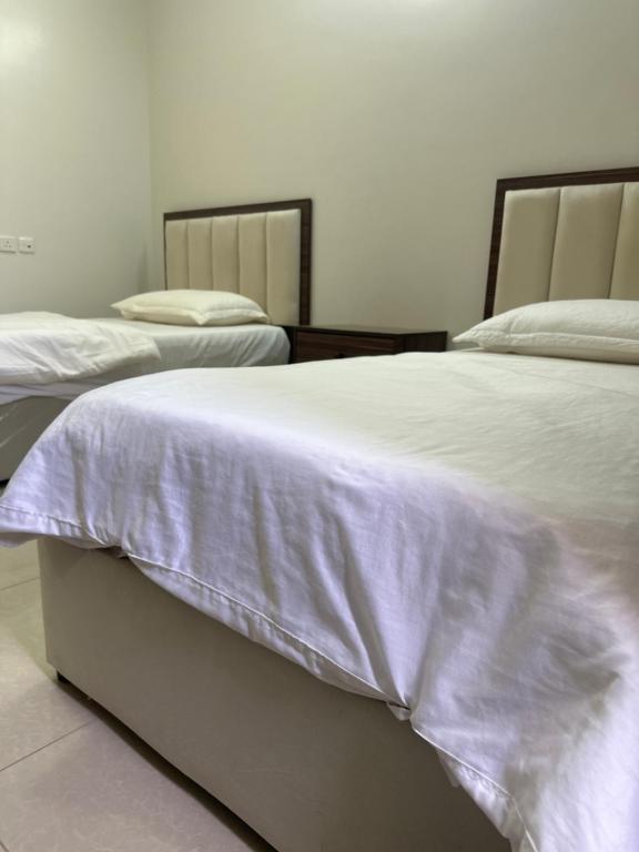 a bedroom with two beds with white sheets at ديار الكرم للشقق المفروشه in Baljurashi