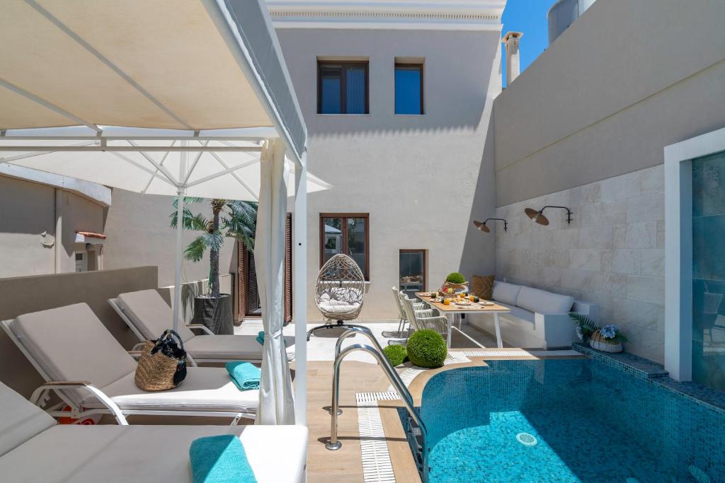 a patio with a pool and chairs and an umbrella at Kallisti Palace - Private Pool with Hydromassage in Kissamos