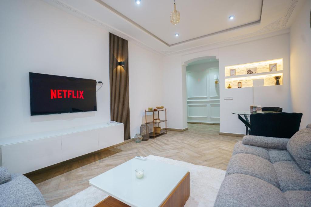Una sala de estar con un sofá y un televisor en una pared. en Luxury Beachfront Apartment NOUR ''Iris Plage'', en Tánger