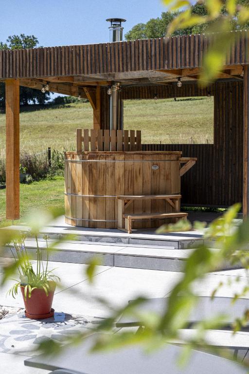 a wooden pergola with a hot tub in a yard at Le Cocon - Domaine du Colombier in Vaux-Marquenneville