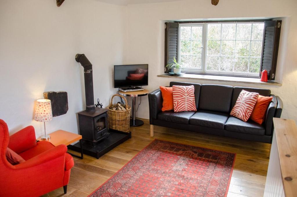 a living room with a black couch and a window at Cleave Cottage in Crackington Haven