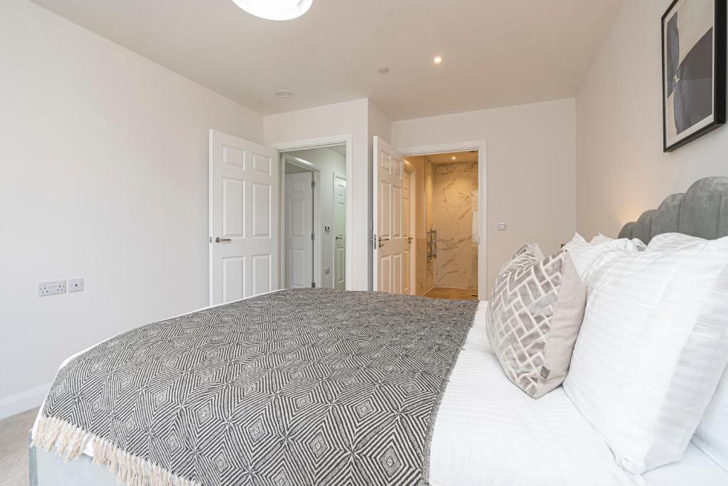 a white bedroom with a bed with white pillows at Birchgrove Christchurch Apartments Exclusively for 65s in Leatherhead