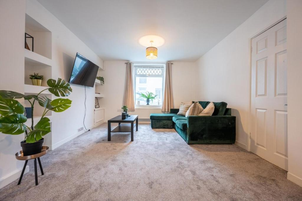 a living room with a green couch and a window at Silver Street by Tŷ SA in Troed-y-rhiw
