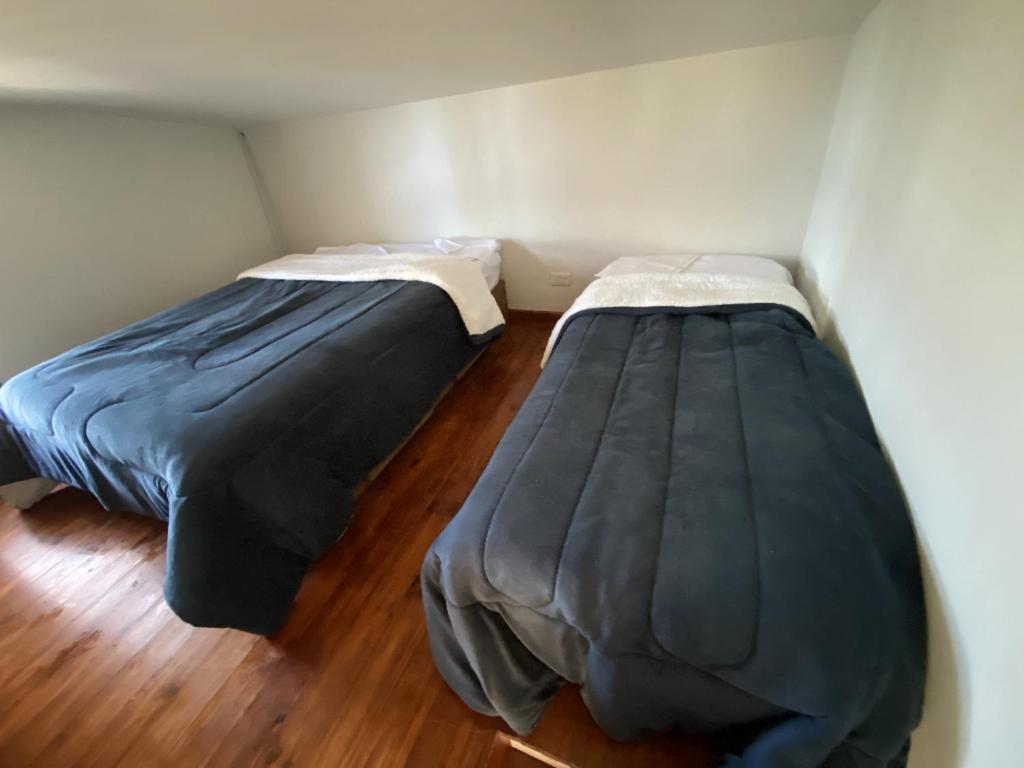 two beds in a small room with wood floors at Cabañas boutique Huella Andina in Potrerillos