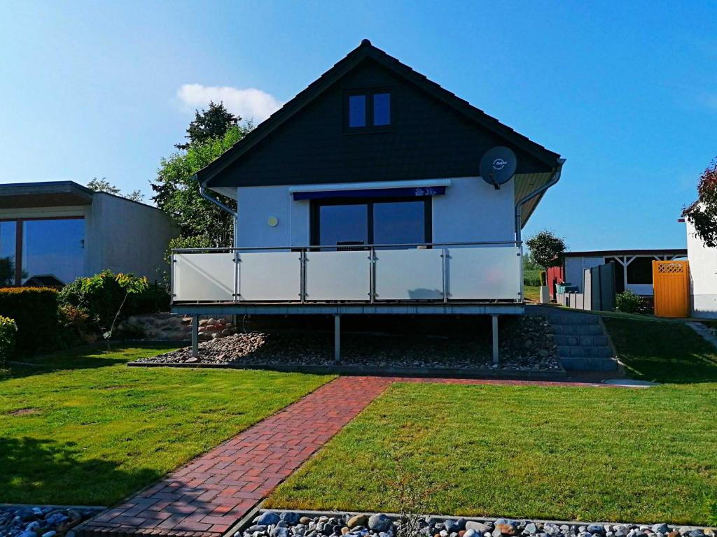 a white house with a black roof and a yard at Ferienhaus Seglerblick am Achterwasser in Ziemitz