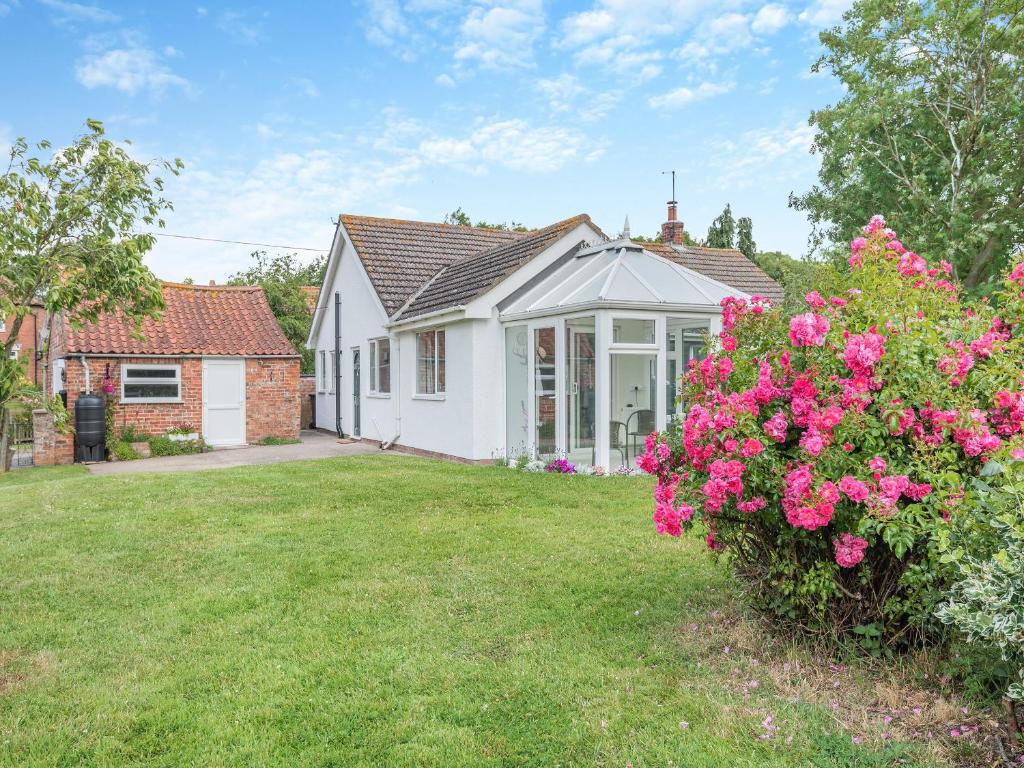 a white house with pink flowers in the yard at Ivy Cottage in Cumberworth