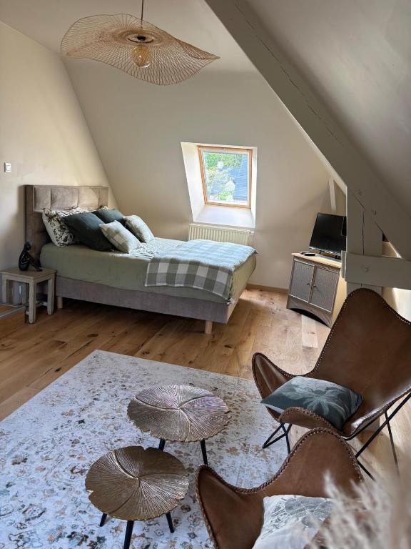 a bedroom with a bed and two chairs and a table at La Maison des Cordiers in Dinan