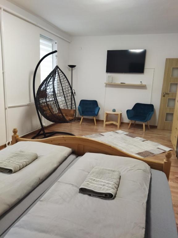 two beds in a room with two chairs and a flat screen tv at Márti Apartman in Sátoraljaújhely