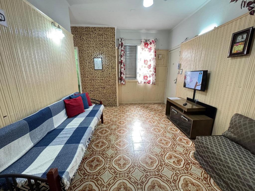 ein Wohnzimmer mit einer blauen Couch und einem Fernseher in der Unterkunft Apto 1 quadra da Praia do Forte c/ Wi-Fi in Praia Grande