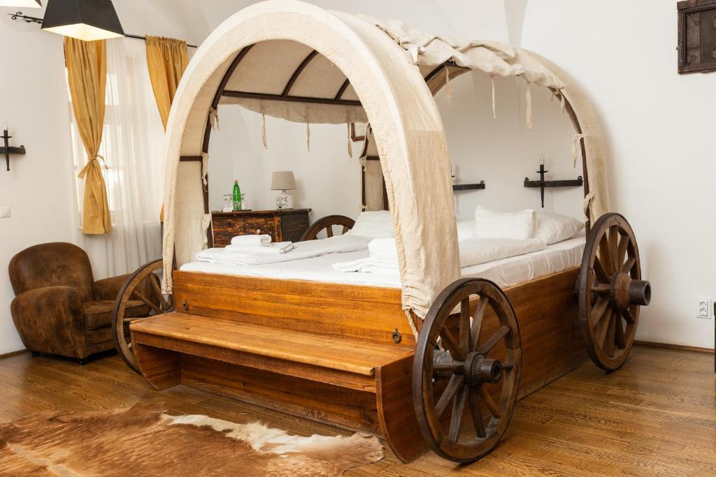 a bedroom with a wooden bed withoked wheels and a chair at Régi Posta Hotel és Étterem in Debrecen