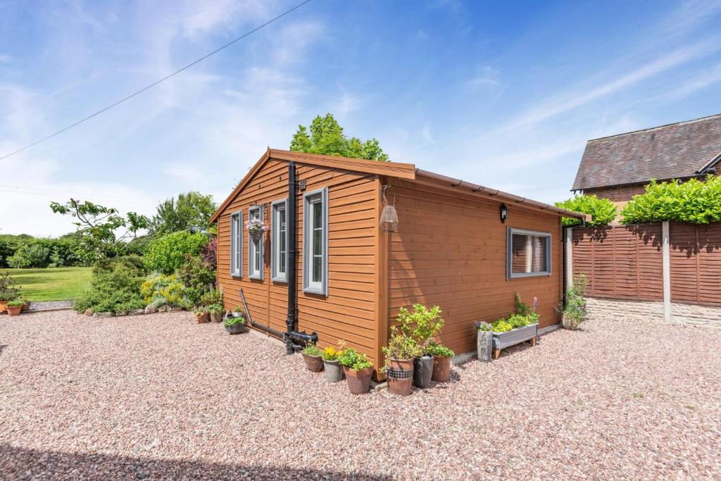 a tiny house with potted plants in a yard at 1 Bed in Lawnhead oc-w32576 in Gnosall