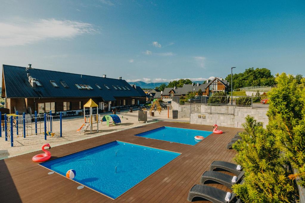 an outdoor playground with two swimming pools and chairs at Osada Śnieżka koło Karpacza in Łomnica