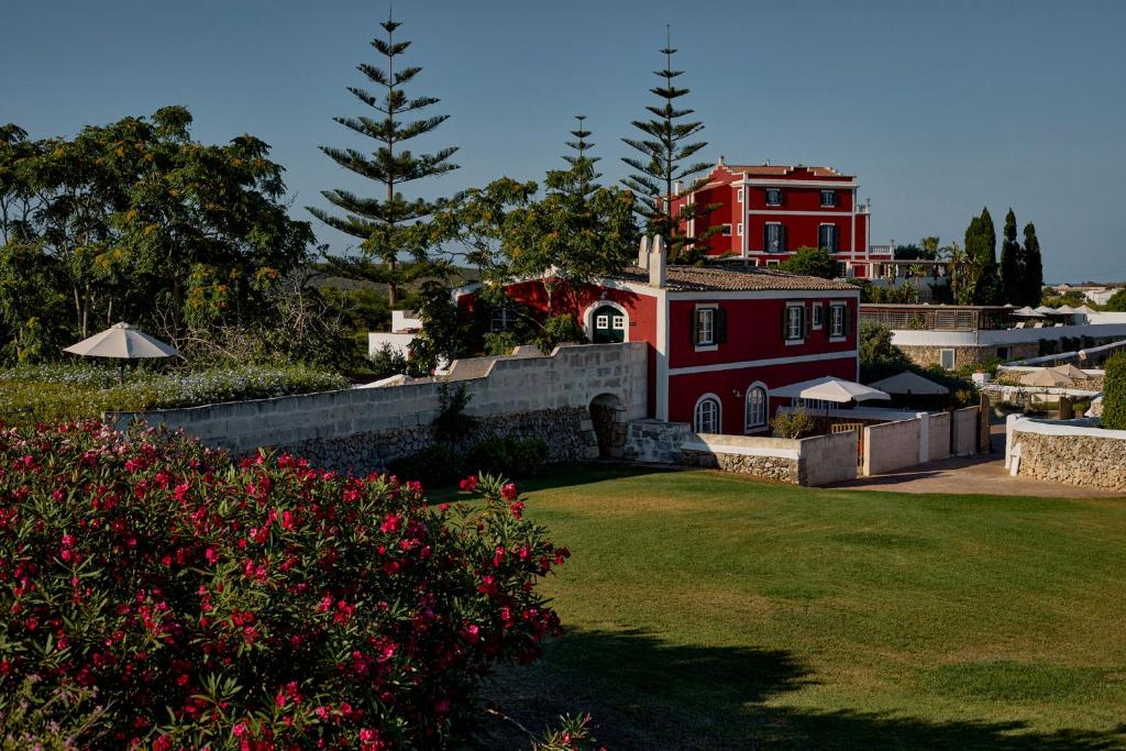a red house with a red building in the background at Son Granot Hotel Rural in Es Castell