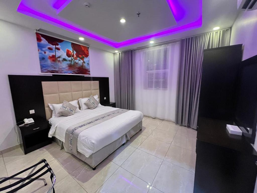 a bedroom with a large bed with purple lighting at الأجنحة المثالية للشقق المخدومة in Taif