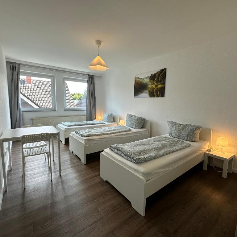 a room with two beds and a table and a chair at WDI - Workers Apartments in Herten