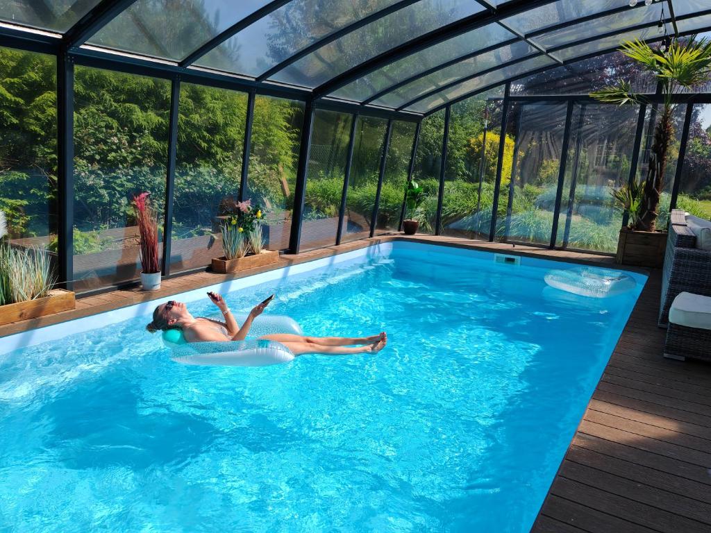 a woman laying in a swimming pool in a greenhouse at Strefa ZEN z Jacuzzi i Basenem in Żerniki Wroctawskie